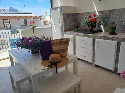 a kitchen with a bench and a table with flowers at Terra Sinus Beautiful Suite in Terrasini