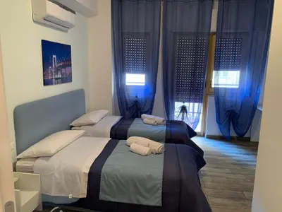 two beds in a room with blue curtains at BONORUM De Spuches in Palermo