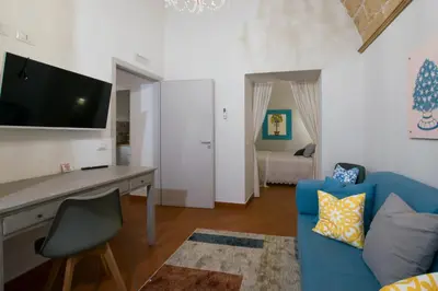 a living room with a blue couch and a desk at Capo Rama Suites & Rooms in Terrasini
