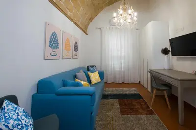 a living room with a blue couch and a desk at Capo Rama Suites & Rooms in Terrasini
