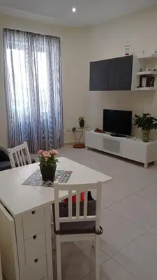 a living room with a white table and a tv at Casetta Delia in Palermo