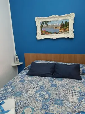 a blue bedroom with a bed and a mirror at Sicilia bedda 1 in Isola delle Femmine