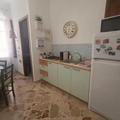a kitchen with a refrigerator and a sink and a clock at Sicilia bedda 1 in Isola delle Femmine
