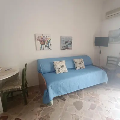 a living room with a blue couch and a table at Sicilia bedda 1 in Isola delle Femmine