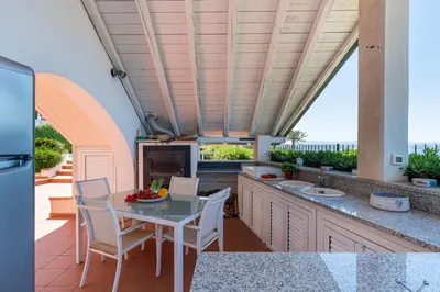 an outdoor kitchen with a table and chairs and a fireplace at Splendida Villa con vista mozzafiato e piscina in Terrasini