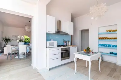 a kitchen with white cabinets and a table and a dining room at Splendida Villa con vista mozzafiato e piscina in Terrasini