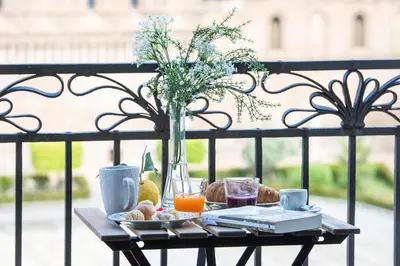 a table with a plate of food and a vase of flowers at Cathedral View Apartments in Palermo
