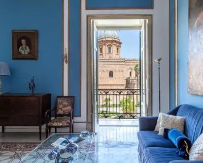 a living room with a blue couch and a view of a building at Cathedral View Apartments in Palermo
