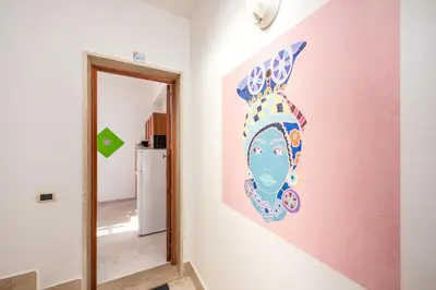a wall with a painting of a head on a wall at I Tre Golfi Beach Apartments in San Vito lo Capo