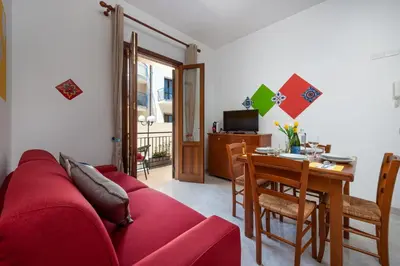 a living room with a red couch and a table at I Tre Golfi Beach Apartments in San Vito lo Capo