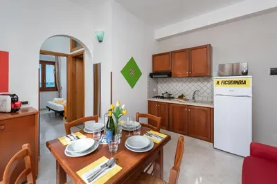 a kitchen and dining room with a wooden table and chairs at I Tre Golfi Beach Apartments in San Vito lo Capo