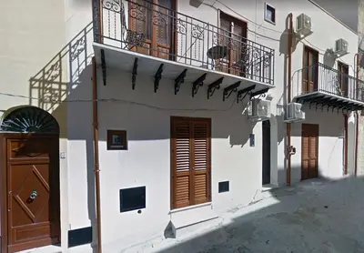 a white building with a balcony and a door at Monolocali Leonardo in Castellammare del Golfo