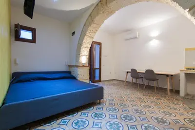 a bedroom with a bed and a table and chairs at Monolocali Leonardo in Castellammare del Golfo