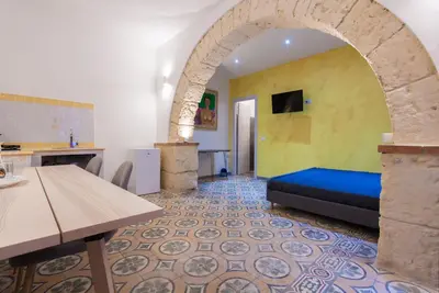 a living room with a blue couch and a yellow wall at Monolocali Leonardo in Castellammare del Golfo