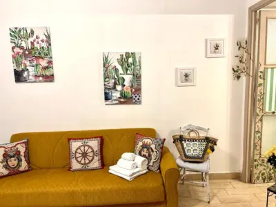 a living room with a yellow couch and paintings on the wall at La Siciliana-di fronte la Cattedrale in Palermo