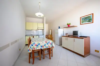 a kitchen with a table with chairs and a refrigerator at Appartamento Blusanvito 1° Piano in San Vito lo Capo