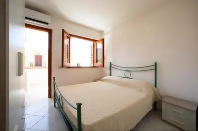 a bedroom with a bed and two windows at Appartamento Blusanvito 1° Piano in San Vito lo Capo