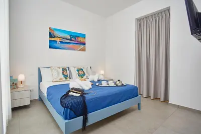 a bedroom with a bed with a blue comforter at Villa Etesiae in Castellammare del Golfo