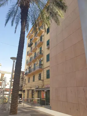a tall building with two palm trees in front of it at Casa del Capo in Palermo