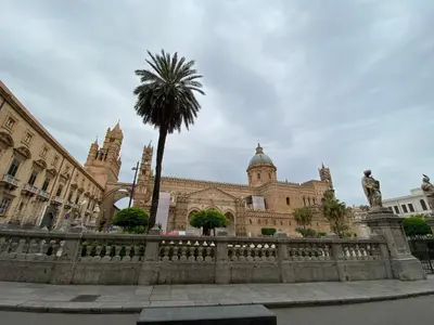 a building with a palm tree in front of a fence at La Piccola Formica Charme Rooms in Palermo