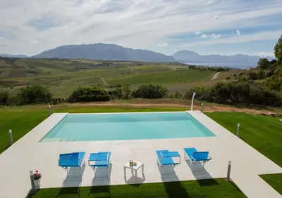 an image of a swimming pool with chairs and a table at Case Playa Resort in Balestrate