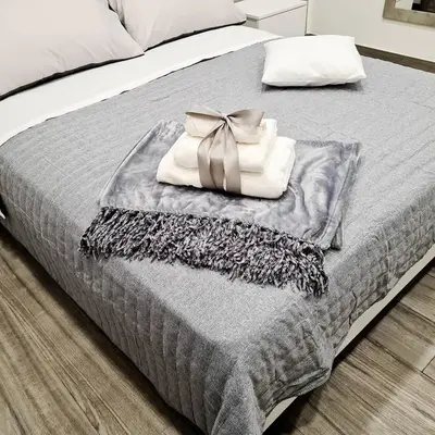 a bed with a gray blanket with a bow on it at La Casa Di Amalia in Palermo