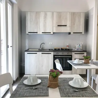 a kitchen with white cabinets and a table with plates at La Casa Di Amalia in Palermo