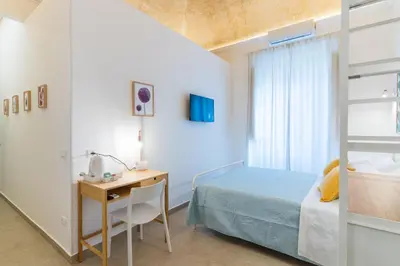a bedroom with a bed and a desk and a bunk bed at Mama Tita Rooms and Breakfast in Palermo