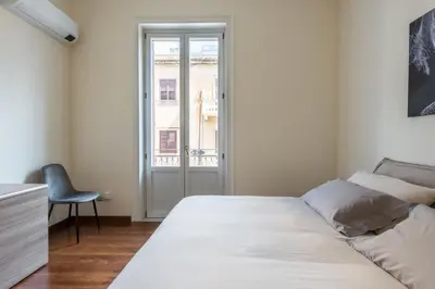 a bedroom with a bed and a chair and a window at Anna's Luxury Apartment in Palermo