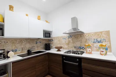 a kitchen with white cabinets and a stove top oven at Fervore Luxury Rooms in Palermo