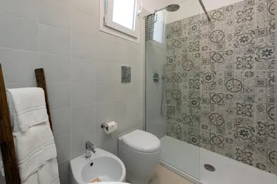a white bathroom with a toilet and a shower at Scrusciu du mari in San Vito lo Capo
