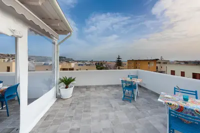 a balcony with blue chairs and a white fence at Scrusciu du mari in San Vito lo Capo