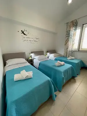 three beds in a room with blue sheets at Casa vacanza 