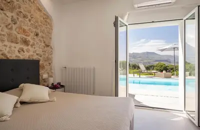 a bedroom with a bed and a view of a pool at Curina Luxury Villa - Panoramic Pool Villa near Scopello in Castellammare del Golfo