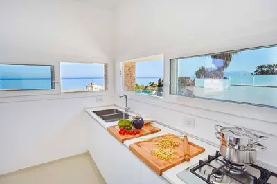 a kitchen with a counter with a sink and two windows at VILLA DARDA con piscina e 3 camere da letto in Alcamo