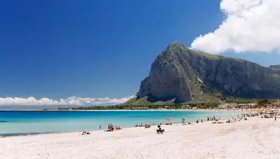 a group of people on a beach with a mountain in the background at Stella del Mare San Vito Lo Capo in San Vito lo Capo