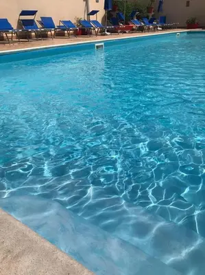 a pool of blue water with chairs in it at Stella del Mare San Vito Lo Capo in San Vito lo Capo