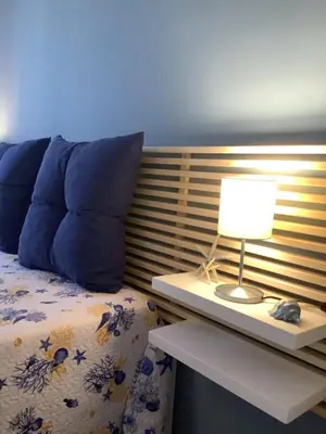 a bed with blue pillows and a table with a lamp at Stella del Mare San Vito Lo Capo in San Vito lo Capo