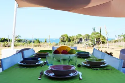 a green table with plates and bowls of fruit on it at Splendida Villa NATURE-APPARTAMENTO MELOGRANO a SCOPELLO-ZINGARO vista sul mare in Scopello