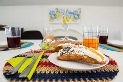 a table with a plate of pastries and orange juice at Splendida Villa NATURE- APPARTAMENTO ARANCIO a Scopello - Zingaro in Scopello