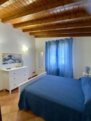 a bedroom with a blue bed and blue curtains at Villa Marcione Garden & House in Cinisi