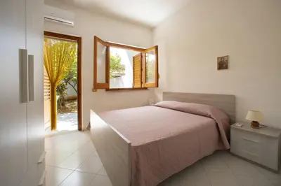 a bedroom with a bed and a mirror and a window at APPARTAMENTI BLUSANVITO P-TERRA in San Vito lo Capo