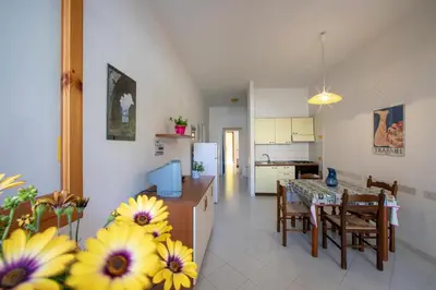 a kitchen and a living room with a table and flowers at APPARTAMENTI BLUSANVITO P-TERRA in San Vito lo Capo
