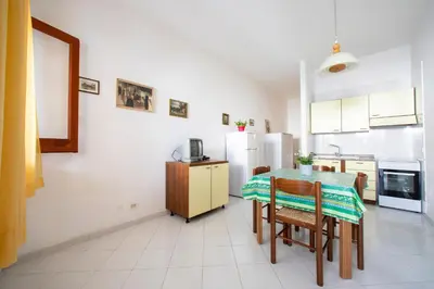 a kitchen with a table and chairs and a refrigerator at APPARTAMENTI BLUSANVITO P-TERRA in San Vito lo Capo