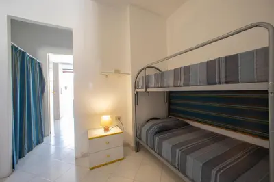 a bedroom with two bunk beds and a lamp on a table at APPARTAMENTI BLUSANVITO P-TERRA in San Vito lo Capo