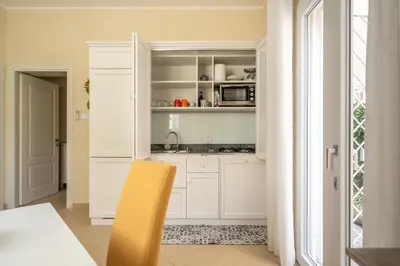 a kitchen with white cabinets and a yellow chair at L'Angolino di Anna in Mondello