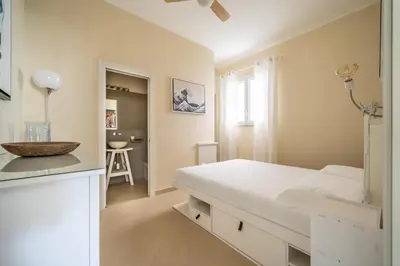 a white bedroom with a bed and a sink at L'Angolino di Anna in Mondello