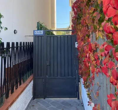 a black gate in front of a wall with red flowers at L'Angolino di Anna in Mondello