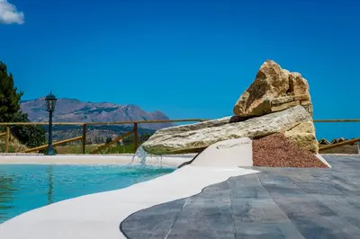a rock fountain next to a swimming pool at Agriturismo Antichi Granai in Calatafimi
