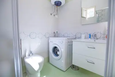 a white bathroom with a washing machine and a sink at Casa in centro in Castellammare del Golfo